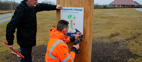 Formanden for Videbæk Borgerforening, Peter Vennevold, gav en hjælpende hånd, da Jacob Christensen fra Ringkøbing-Skjern Kommunes Vej- og Parkafdeling i går satte det første nye Til Salg-skilt op på ledige kommunale grunde i Videbæk